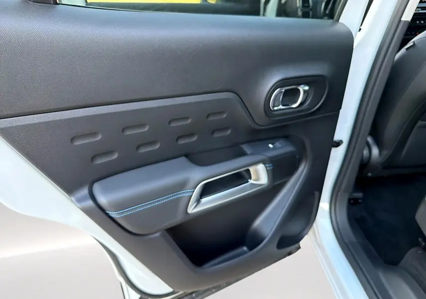 Vue intérieure côté gauche de la porte arrière blanche du Citroën C5 Aircross avec poignée argent et surpiqûres bleues.