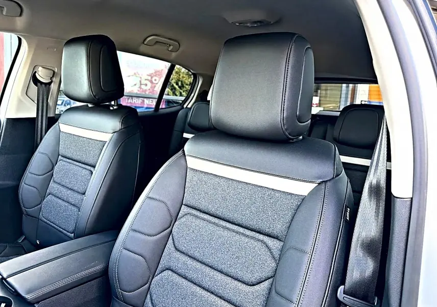 Vue intérieure côté avant droit du Citroën C5 Aircross 2025 blanc, sièges en cuir et tissu noir avec accoudoir central.