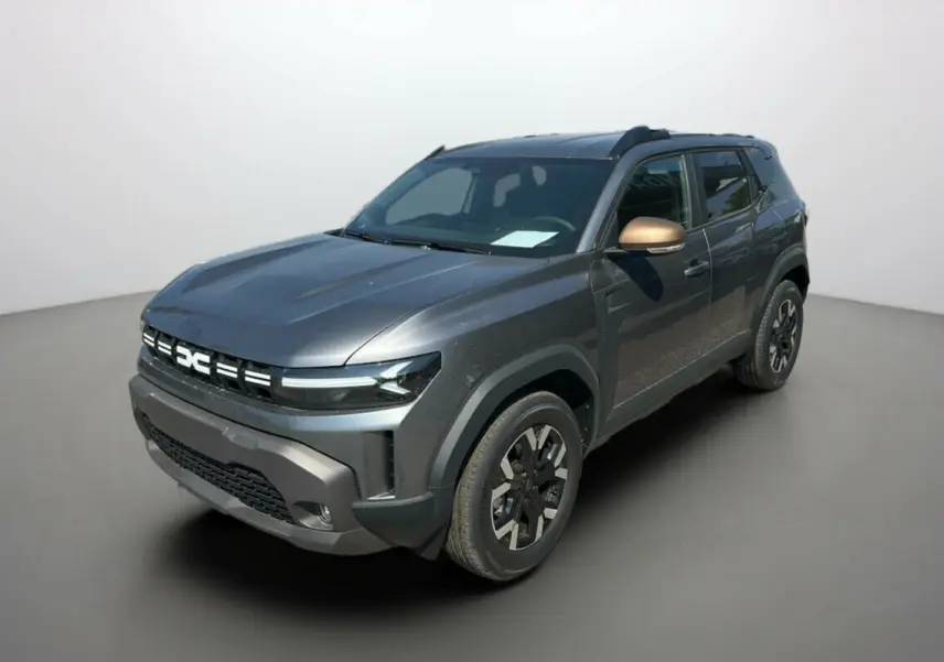 Dacia Duster HEV 140 gris schiste vu en 3/4 avant droit avec rétroviseur bronze et jantes noires distinctives.