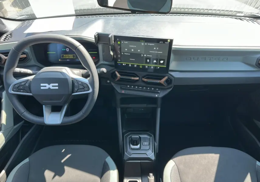 Vue intérieure du tableau de bord du Dacia Duster HEV 140 Extreme Pack Hiver 2025 avec écran tactile et volant multifonction.