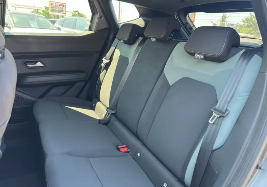 Vue latérale droite des sièges arrière du Dacia Duster 2025 gris schiste avec appuie-têtes et ceintures visibles.