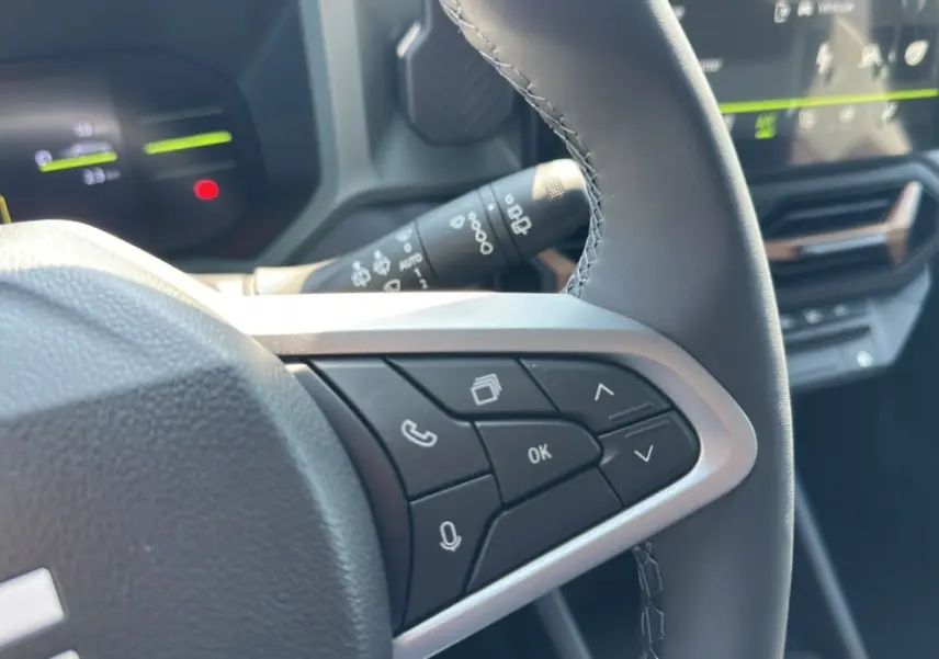 Gros plan sur les commandes au volant du Dacia Duster HEV 140 Extreme Pack Hiver 2025, intérieur noir moderne.