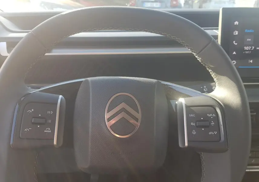 Vue rapprochée du volant noir de la Citroën C3 2024 avec commandes intégrées et tableau de bord numérique.