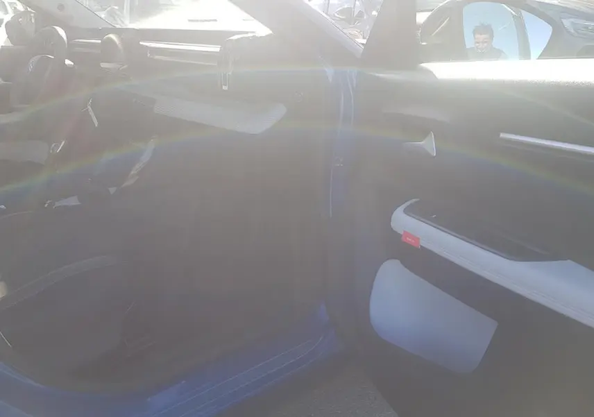 Intérieur de la Citroën C3 bleu foncé 2024 vu côté passager, avec porte ouverte et sellerie noire.