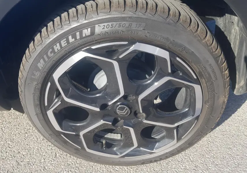 Gros plan sur la jante alliage 17 pouces noire et argentée d'une Citroën C3 bleu foncé, côté gauche.