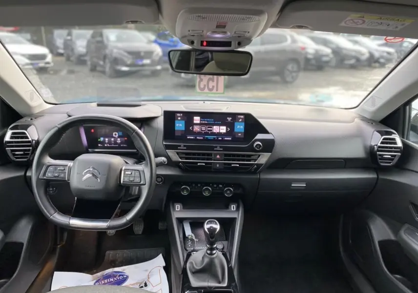 Vue intérieure avant du tableau de bord de la Citroën C4 2021, avec volant, écran tactile et levier de vitesses manuel.