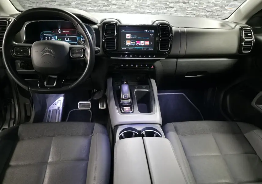 Vue intérieure avant du Citroën C5 Aircross gris, avec tableau de bord numérique et console centrale moderne.