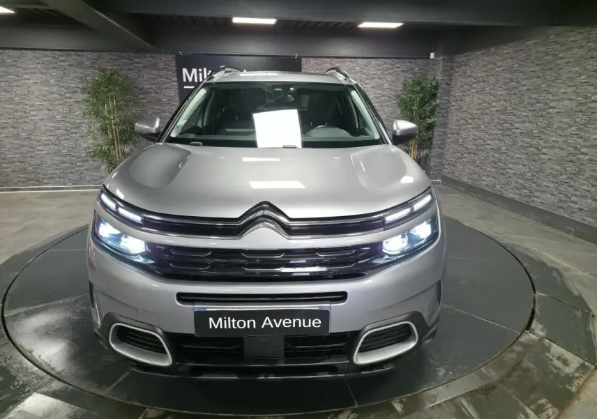 Vue avant d'un Citroën C5 Aircross gris acier avec feux LED allumés dans un showroom.