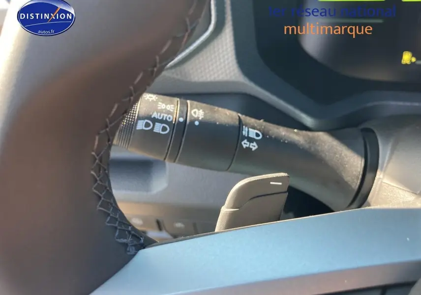 Gros plan sur le commodo des feux et la palette de changement de vitesse derrière le volant d’un Dacia Duster kaki lichen.