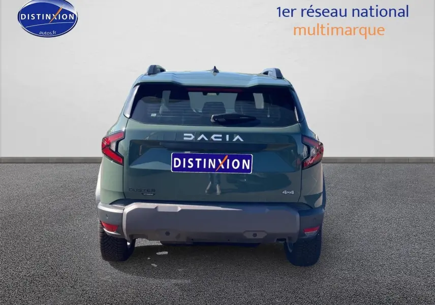 Vue arrière d'un Dacia Duster 1.2 hybrid-g 150 expression 4x4 en kaki lichen avec barres de toit et becquet.
