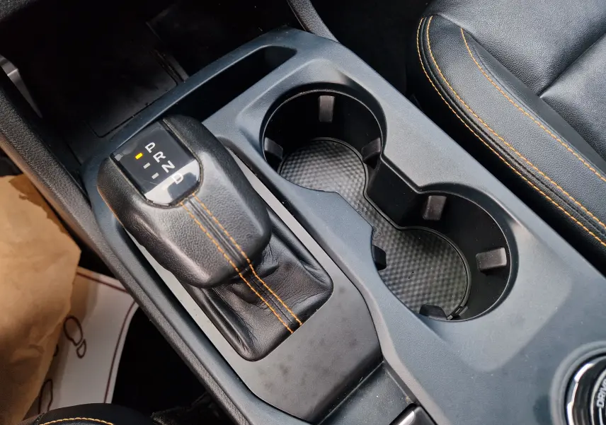 Gros plan sur le levier de vitesse automatique noir avec surpiqûres orange et porte-gobelets du Ford Ranger Wildtrak 2023.