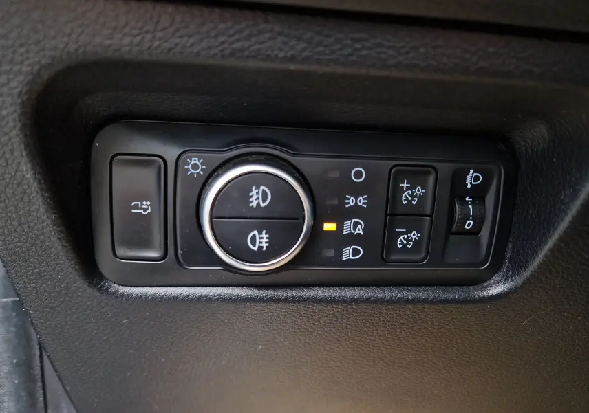 Gros plan sur le panneau de commandes d’éclairage intérieur noir du Ford Ranger Wildtrak 2023, avec bouton rotatif et indicateurs lumineux.