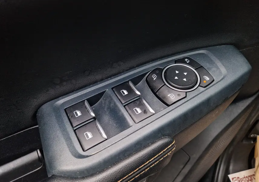 Gros plan sur les commandes de lève-vitres et rétroviseurs côté conducteur du Ford Ranger Wildtrak noir 2023.