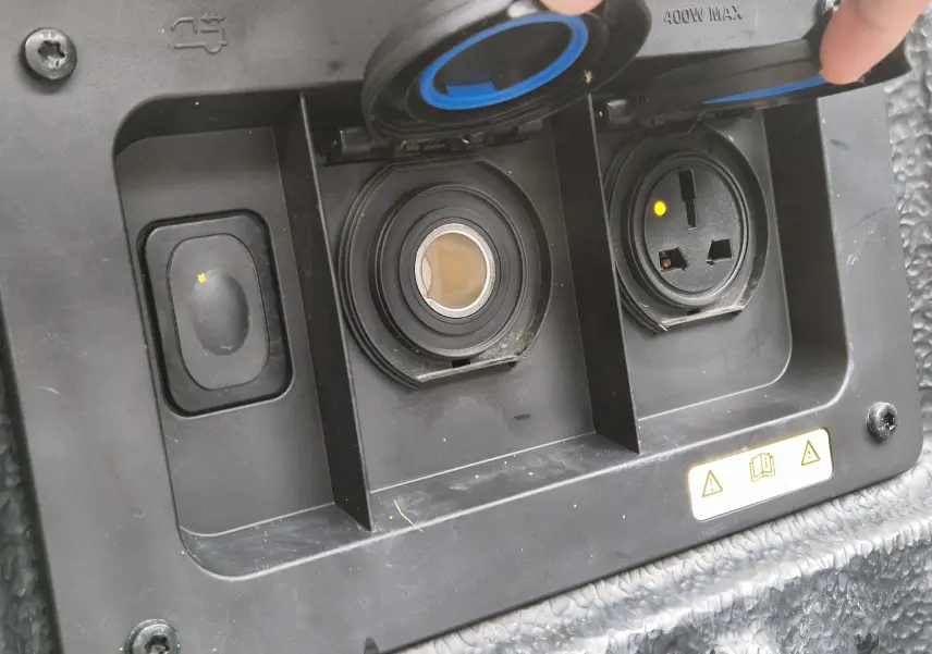 Gros plan sur les prises électriques et allume-cigare du Ford Ranger Wildtrak noir, avec couvercles ouverts.