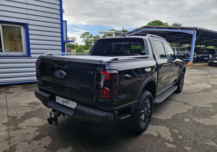 Ford Ranger Double Cabine noir vu en 3/4 arrière droit, avec rideau de plateau coulissant et marchepied visible.