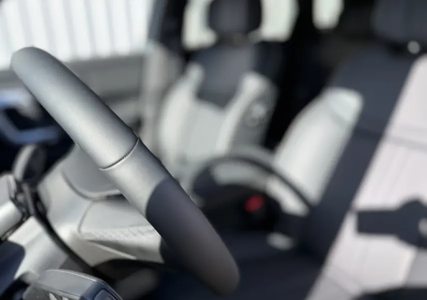 Gros plan sur le volant et siège avant gris clair de l’intérieur du JAECOO J7 PHEV 2026, ambiance lumineuse naturelle.