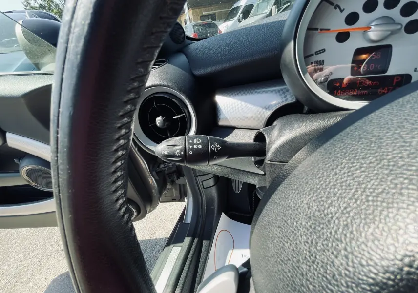 Vue rapprochée du tableau de bord côté gauche d'une MINI Cooper S grise, avec volant et compteur visibles.