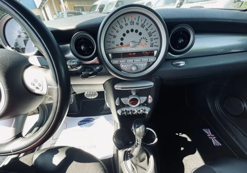 Vue intérieure du tableau de bord et console centrale d'une MINI Cooper S grise avec levier de vitesse automatique et détails chromés.