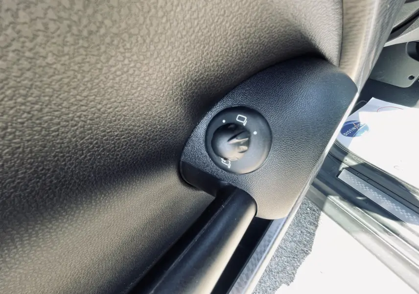 Gros plan sur le bouton de réglage des rétroviseurs côté conducteur dans une MINI Cooper S gris 2008.
