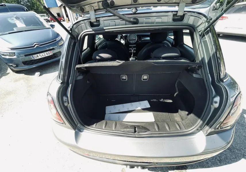 Coffre ouvert d'une MINI Cooper S gris, vue arrière montrant l'intérieur et les sièges avant.