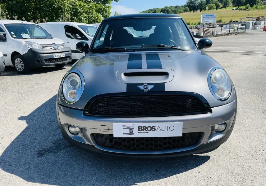 Vue frontale d'une MINI Cooper S gris métallisé avec bandes noires sur le capot et calandre noire brillante.