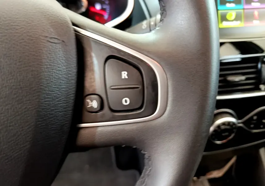 Gros plan sur le volant cuir noir de la Renault Clio Business TCe 90 avec commandes audio et tableau de bord partiellement visible.