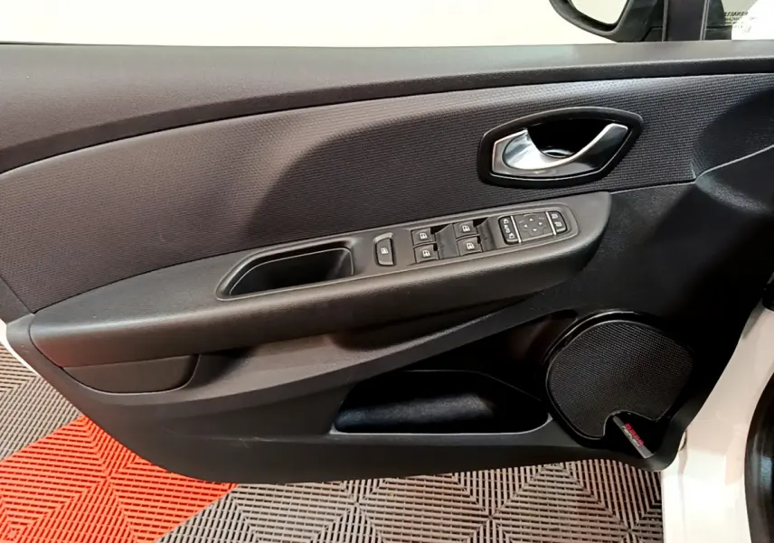 Gros plan sur la porte avant gauche noire de la Renault Clio blanche, avec commandes électriques et haut-parleur intégré.