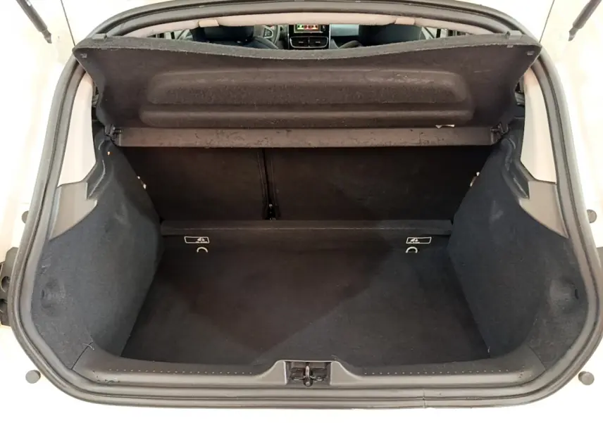 Coffre ouvert d'une Renault Clio Business blanche, vue de l'arrière montrant l'espace de chargement vide et la tablette arrière.
