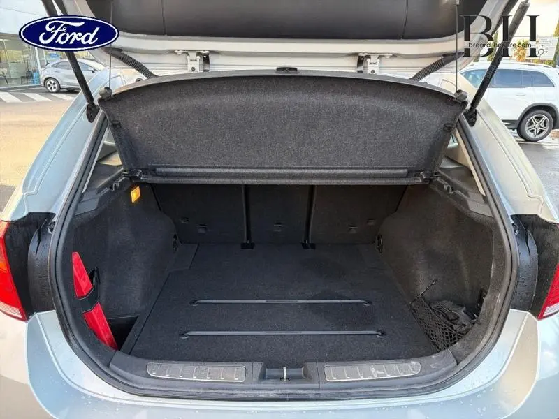 Coffre ouvert d'un BMW X1 Mineralgrau vu de l'arrière, montrant un espace de chargement propre avec filet latéral et cache-bagages.
