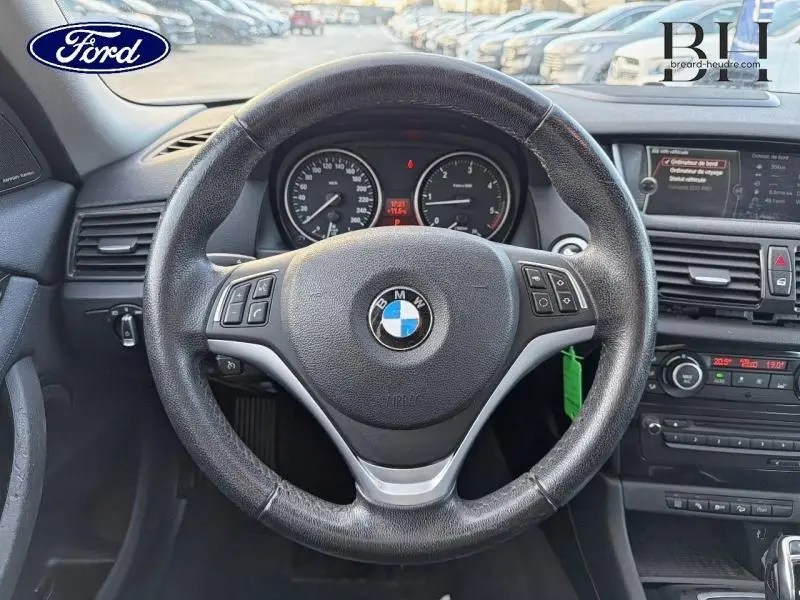 Vue rapprochée du volant cuir multifonction noir de la BMW X1 xDrive25dA 2014, tableau de bord et console centrale visibles.