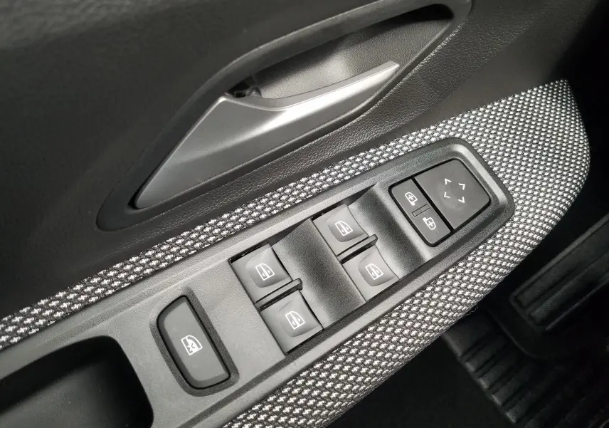 Détail des commandes des vitres et rétroviseurs sur la porte côté conducteur d'une Dacia Sandero Stepway 2025.