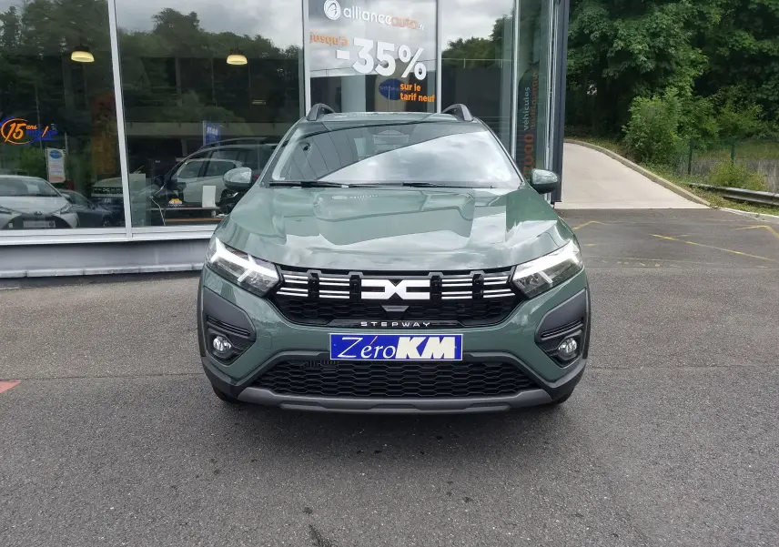 Vue frontale d'une Dacia Sandero Stepway 2025 en Licken Kaki avec calandre noire et feux LED allumés.