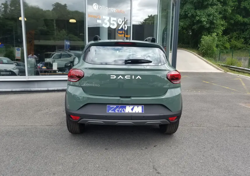 Vue arrière d'une Dacia Sandero Stepway 2025 en vert Licken Kaki avec barres de toit et logo visible.