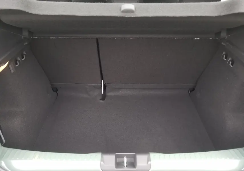 Coffre ouvert vu de l'arrière d'une Dacia Sandero Stepway 2025 en Licken Kaki, intérieur noir et tapis de coffre.