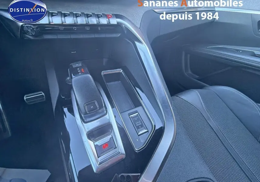 Gros plan sur la console centrale noire brillante du Peugeot 3008 2023, avec levier de boîte auto et siège avant droit en cuir.