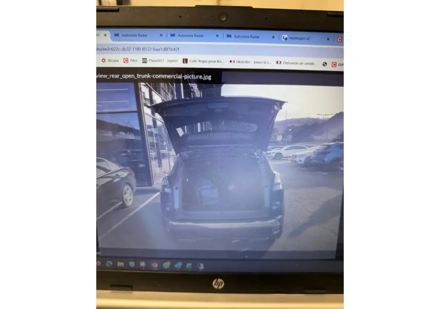 Vue arrière d'un Peugeot 3008 bleu 2023 avec coffre ouvert et intérieur de coffre visible en extérieur urbain.