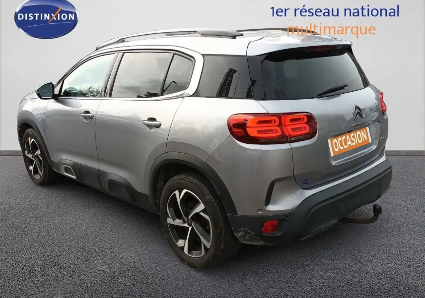 Vue 3/4 arrière droite d'un Citroën C5 Aircross gris Artense métal avec feux arrière LED et attelage visible.