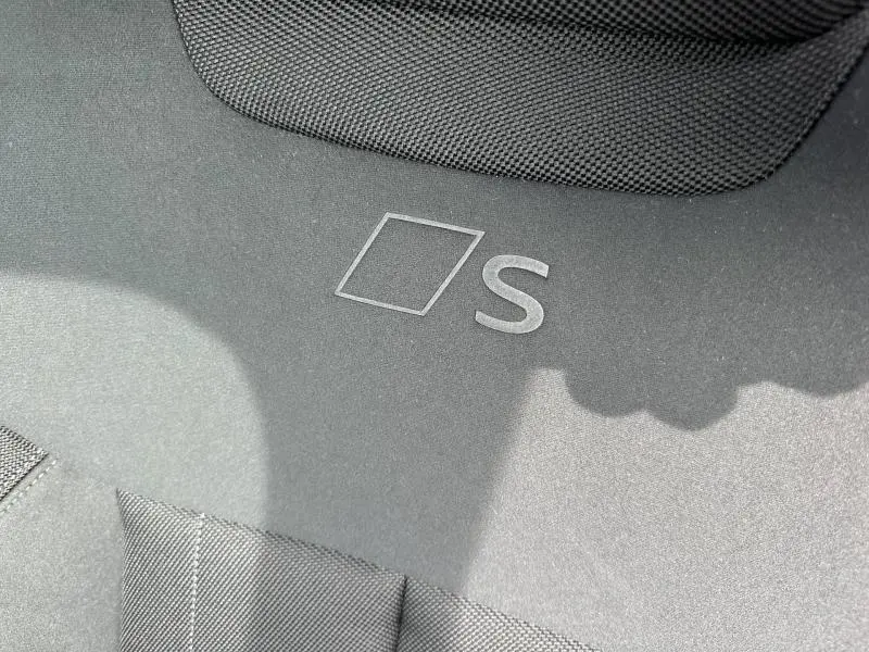 Détail du tapis de sol noir avec logo S dans un Audi Q3 2.0 TDI S line, vue rapprochée intérieure.