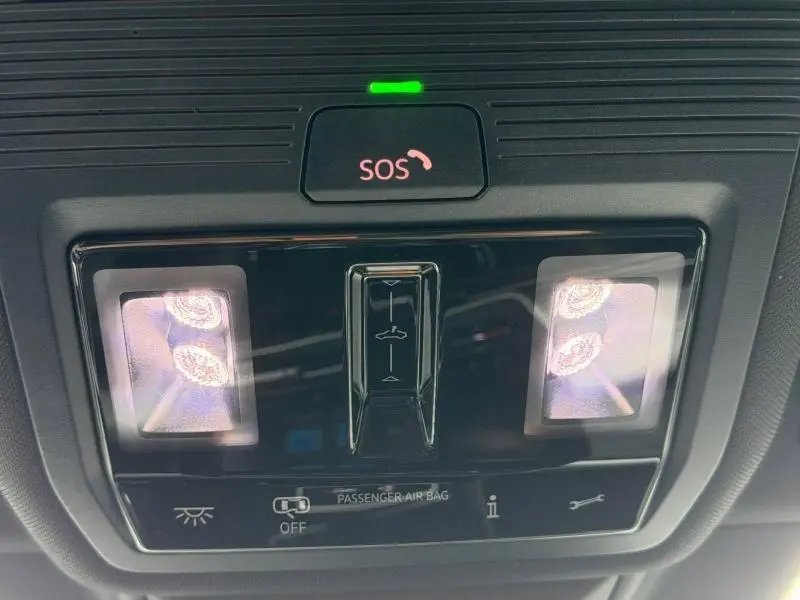 Panneau de commande intérieur avec éclairage et bouton SOS activé, vue en gros plan dans une Volkswagen Golf blanche.