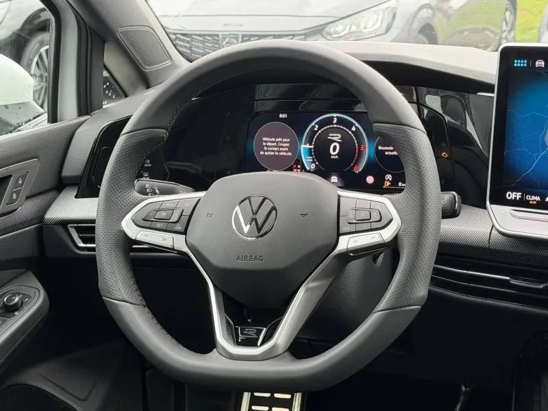 Vue intérieure centrée sur le volant noir perforé d'une Volkswagen Golf 2.0 TDI R-Line 2026 avec tableau de bord numérique.