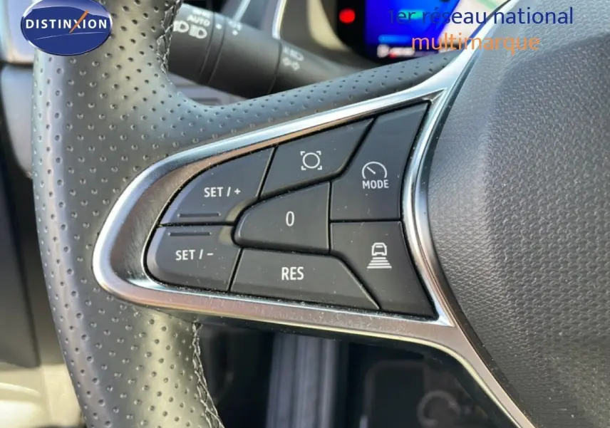 Gros plan sur les commandes au volant en cuir perforé du Renault Symbioz gris Cassiopée, mettant en valeur les boutons de régulateur.