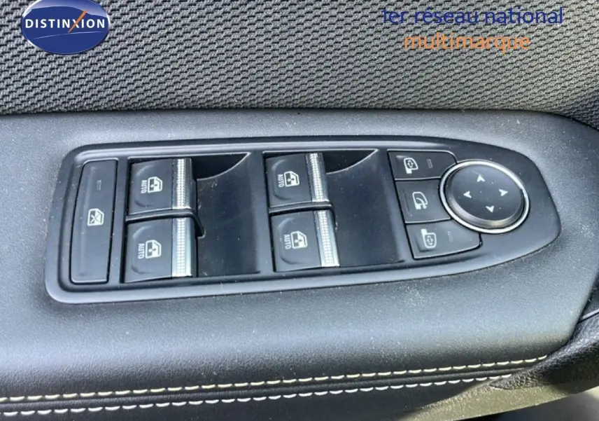 Gros plan sur les commandes des vitres électriques côté gauche d'une Renault Symbioz gris cassiopée métal, intérieur tissu noir.