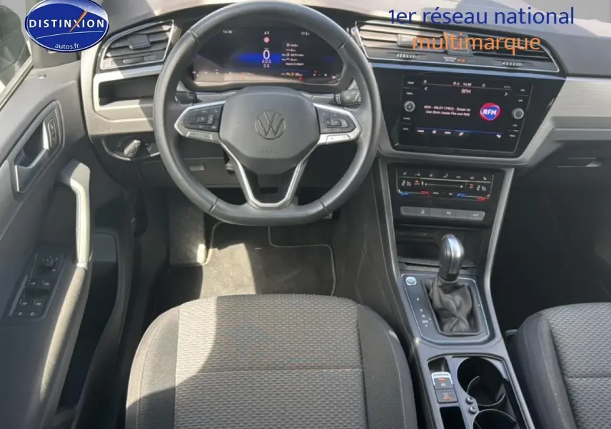 Vue intérieure avant du Volkswagen Touran 2025 noir, volant cuir multifonction et écran tactile central visible.
