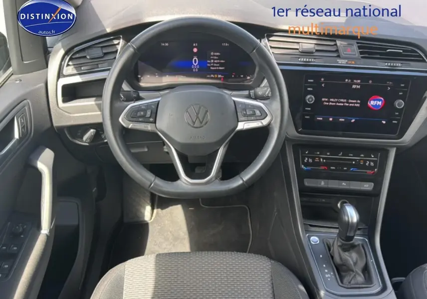 Vue intérieure avant du Volkswagen Touran 2025 noir, montrant le volant cuir multifonction et la console centrale avec écran tactile.