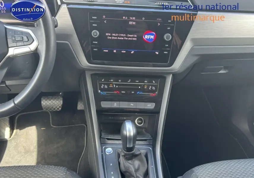 Vue intérieure avant centrée sur la console centrale et le levier de vitesse d’un Volkswagen Touran noir 2025.