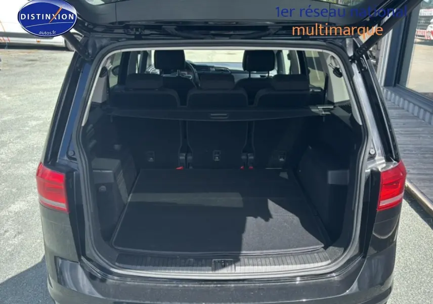 Vue arrière du coffre ouvert d’un Volkswagen Touran noir 2025, montrant la 3ème rangée de sièges et l’espace de chargement.