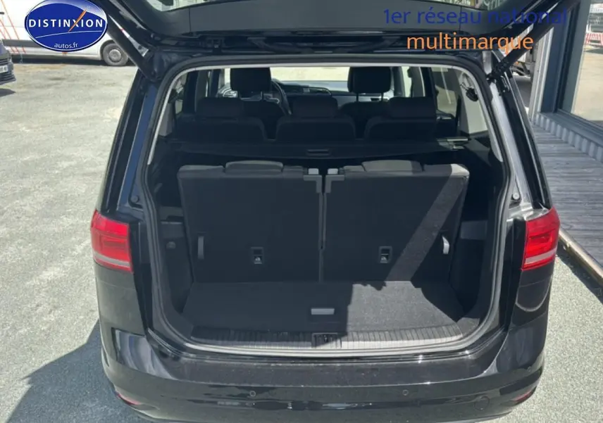 Vue arrière d’un Volkswagen Touran noir 2025 avec coffre ouvert et troisième rangée de sièges visible.