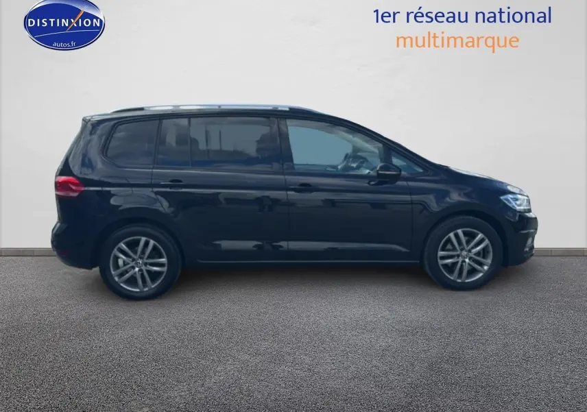 Profil latéral droit d'un Volkswagen Touran noir 2025 avec jantes alliage et vitres surteintées.