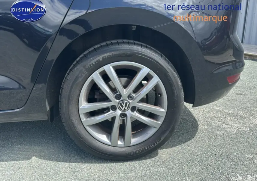 Gros plan sur la roue arrière droite avec jante alu argentée d’un Volkswagen Touran noir.