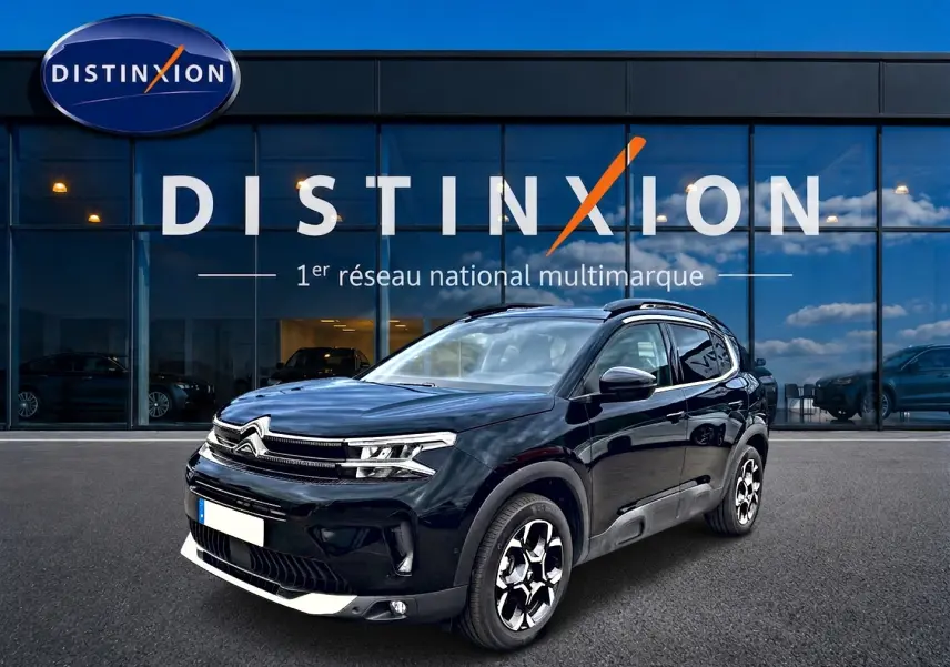Citroën C5 Aircross noir vue 3/4 avant droit, avec jantes alu et barres de toit visibles devant un showroom Distinxion.
